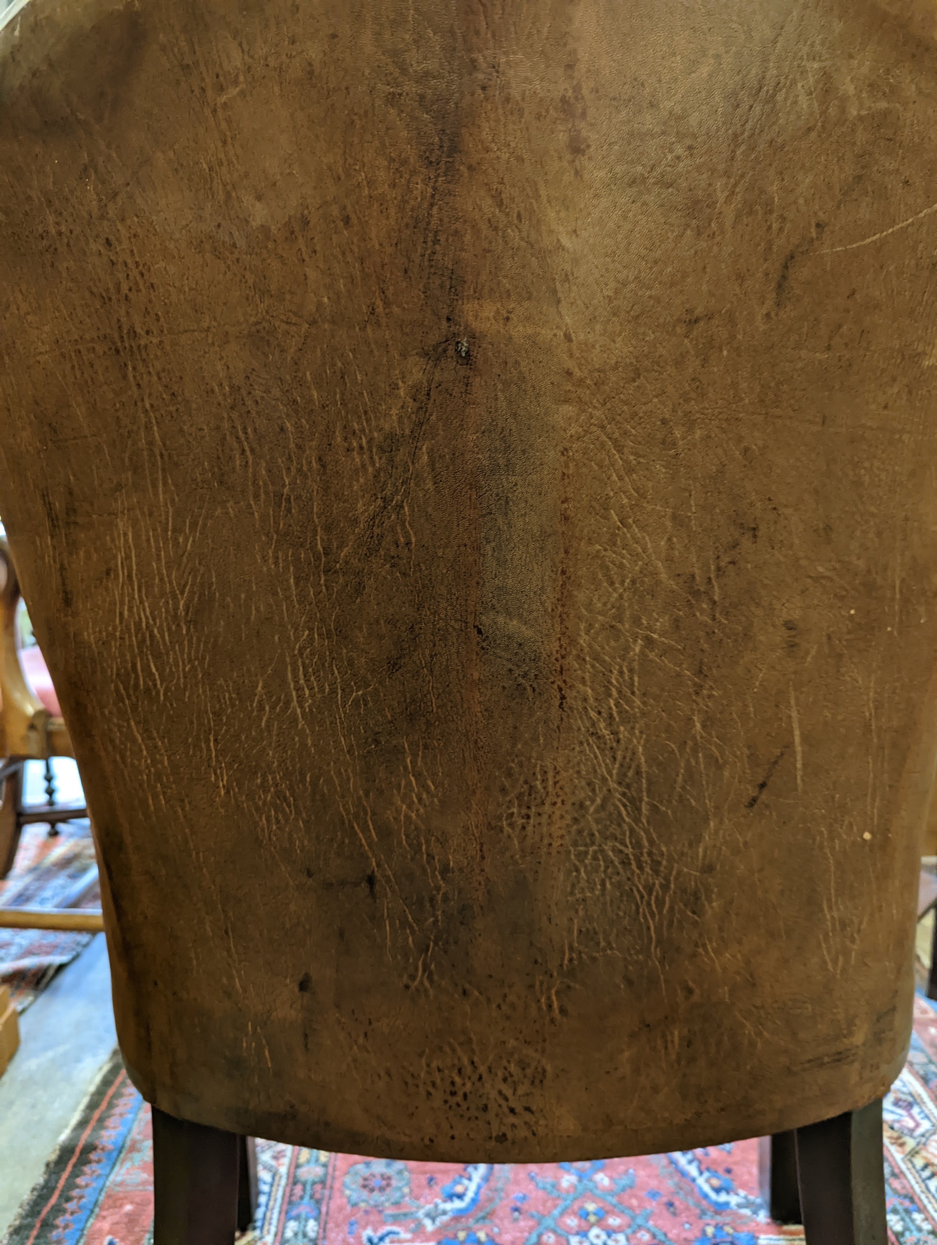 A brown leather upholstered desk chair, a mahogany hall chair and two upholstered armchairs